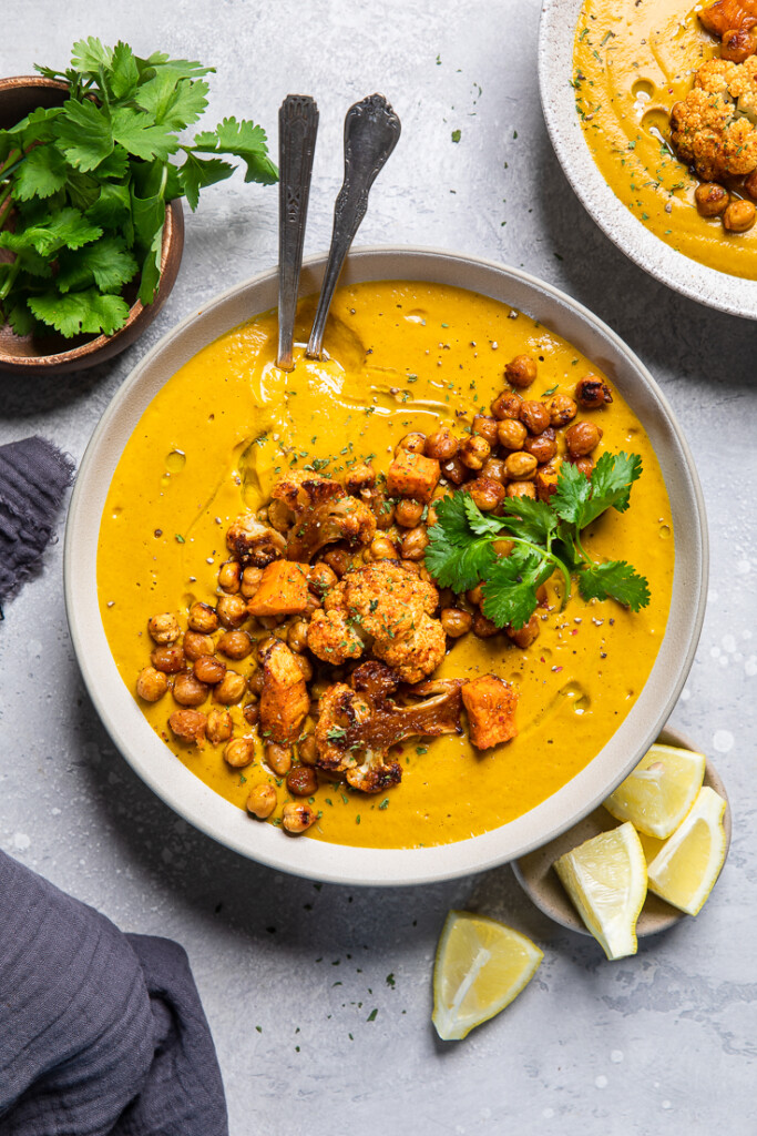 a bowl of vegan golden soup topped with cooked chickpeas and cauliflower. 
