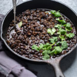A skillet of instant pot black beans with fresh cilantro.