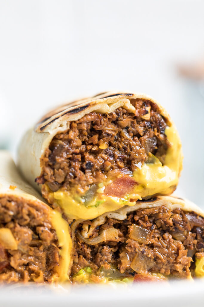 Inside of a vegan cheeseburger wrap with nacho cheese sauce spread at the bottom.