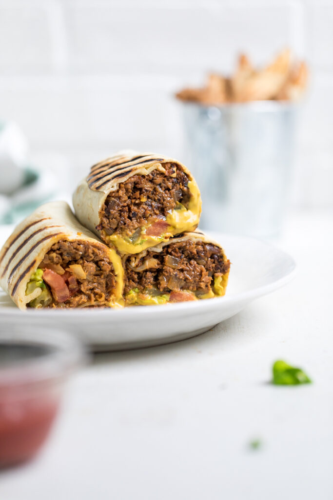 vegan cheeseburger wraps stacked on a plate.