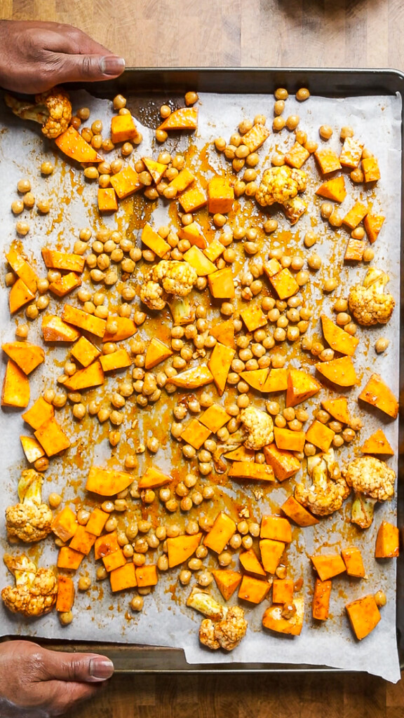cauliflower and sweet potatoes laid out on a sheet pan. 