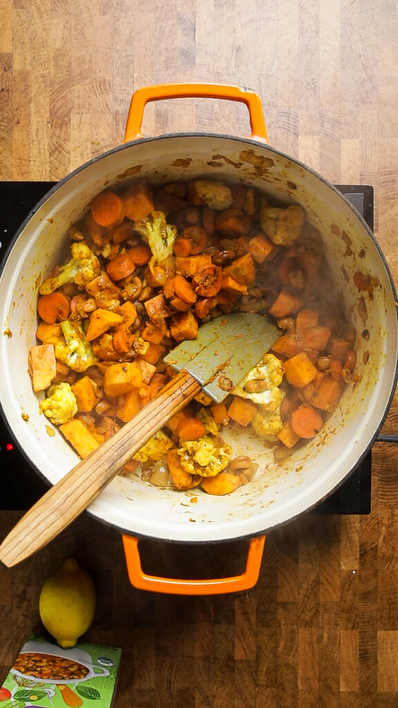 seasoned cauliflower, carrots, and potatoes cooking in a dutch oven. 