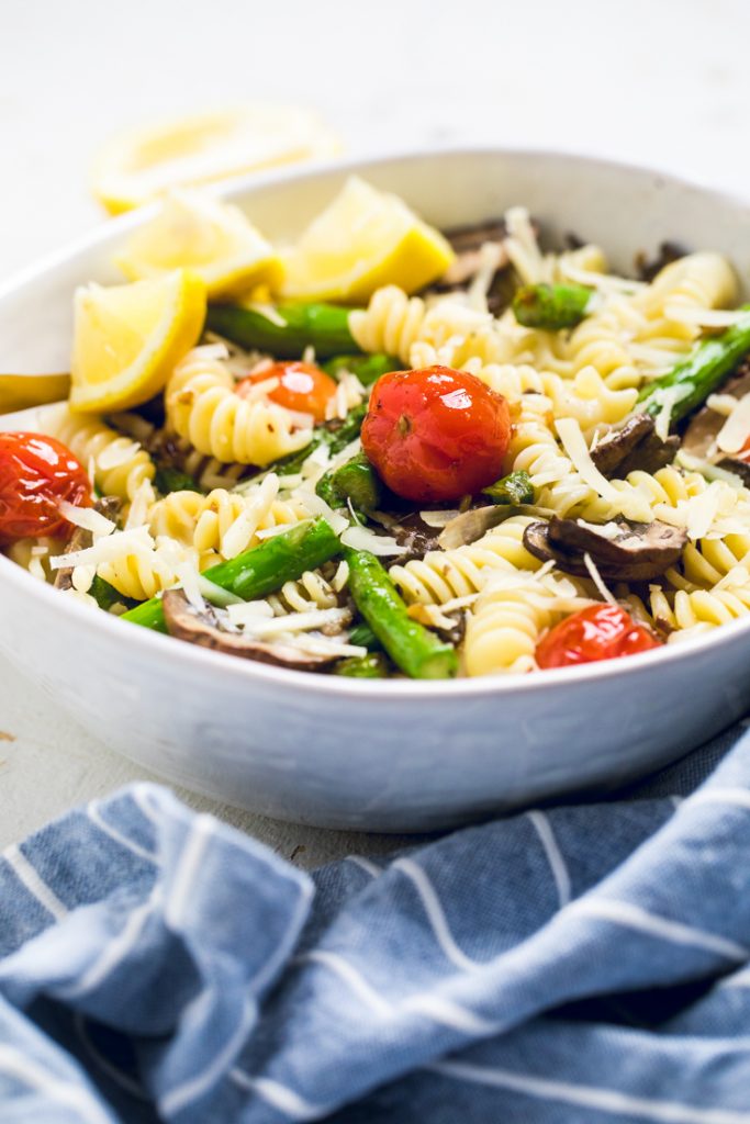 Vegan Lemon Garlic Butter Pasta with Tomatoes, Asparagus and Mushrooms in a white bowl.