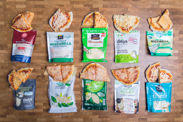 An assortment of homemade vegan pizzas next to vegan cheese packages.