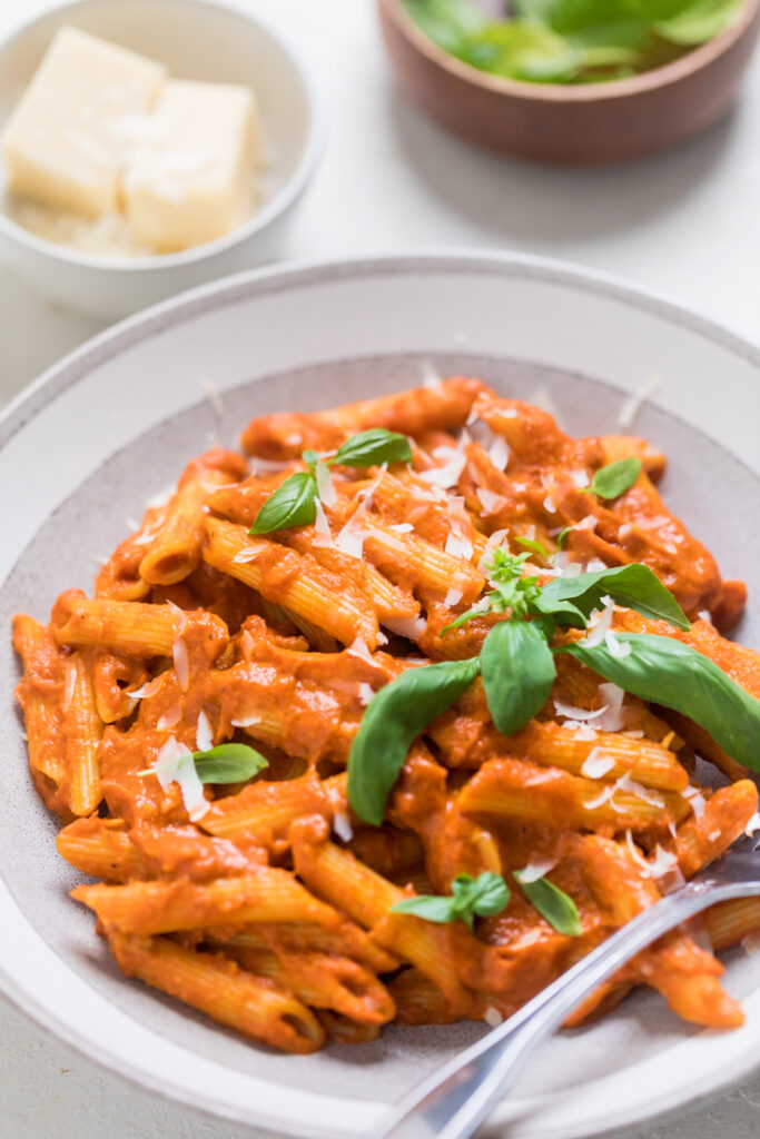 A bowl of penne pasta mixed with vegan vodka sauce.